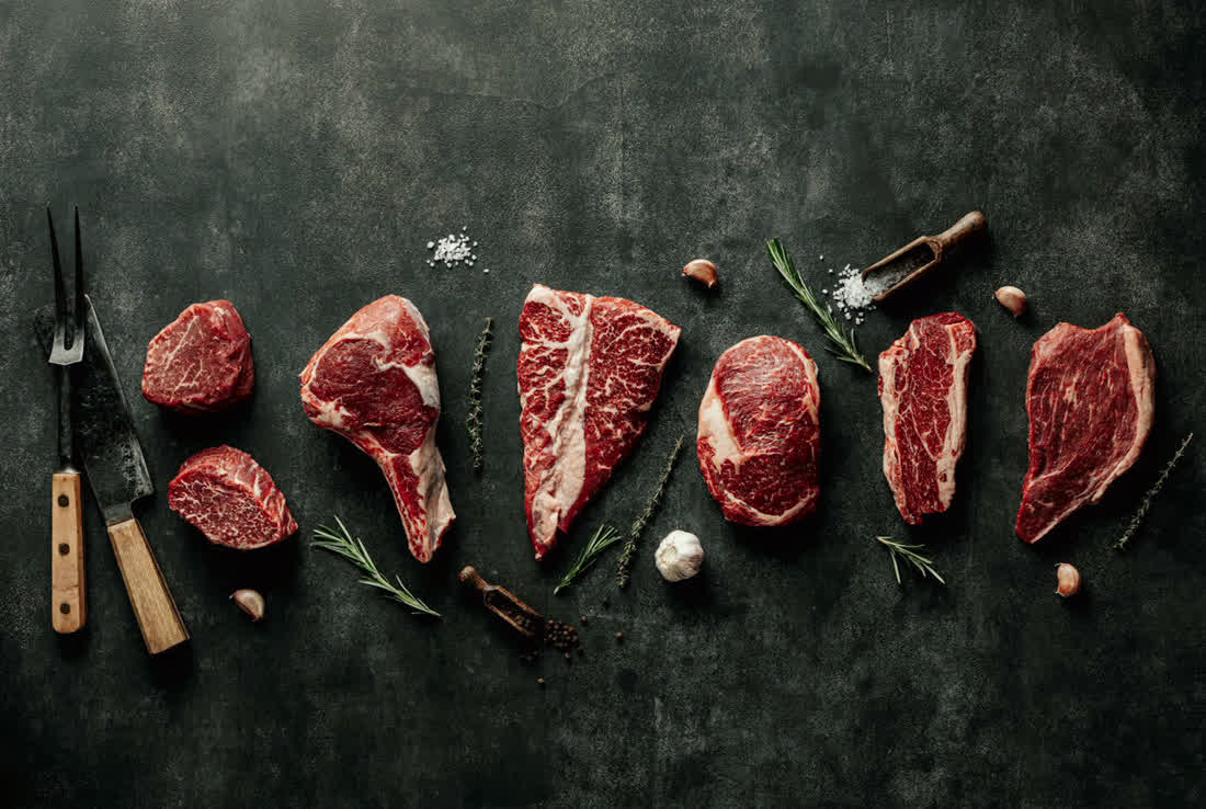 Cuts of raw beef on a dark board
